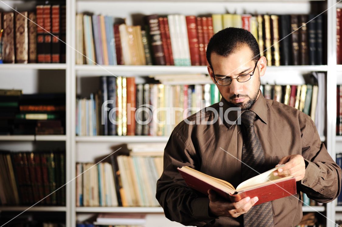 Young man reading book in library