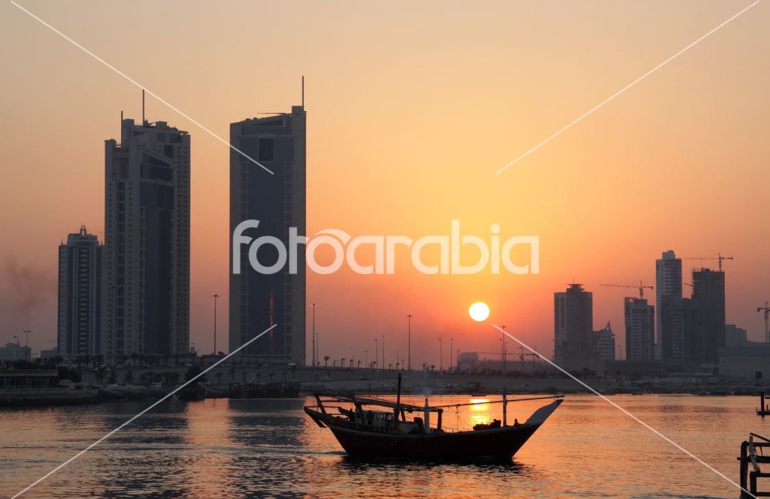 Dhow and Seef skyline during sunset in Bahrain