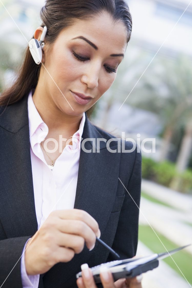 Businesswoman using PDA and earpiece