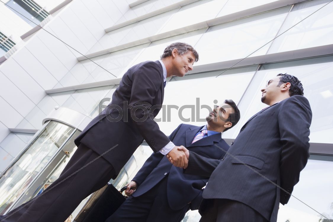 Group of businessmen shaking hands outside office