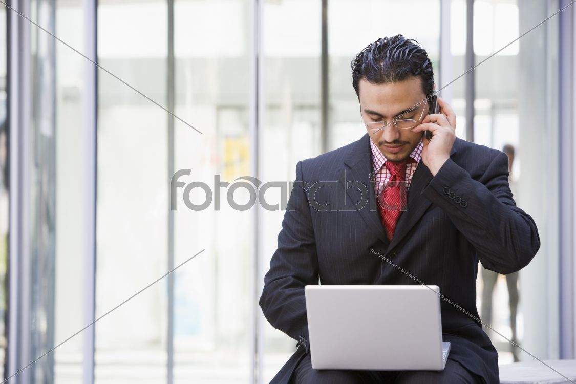 Businessman using laptop and mobile outside