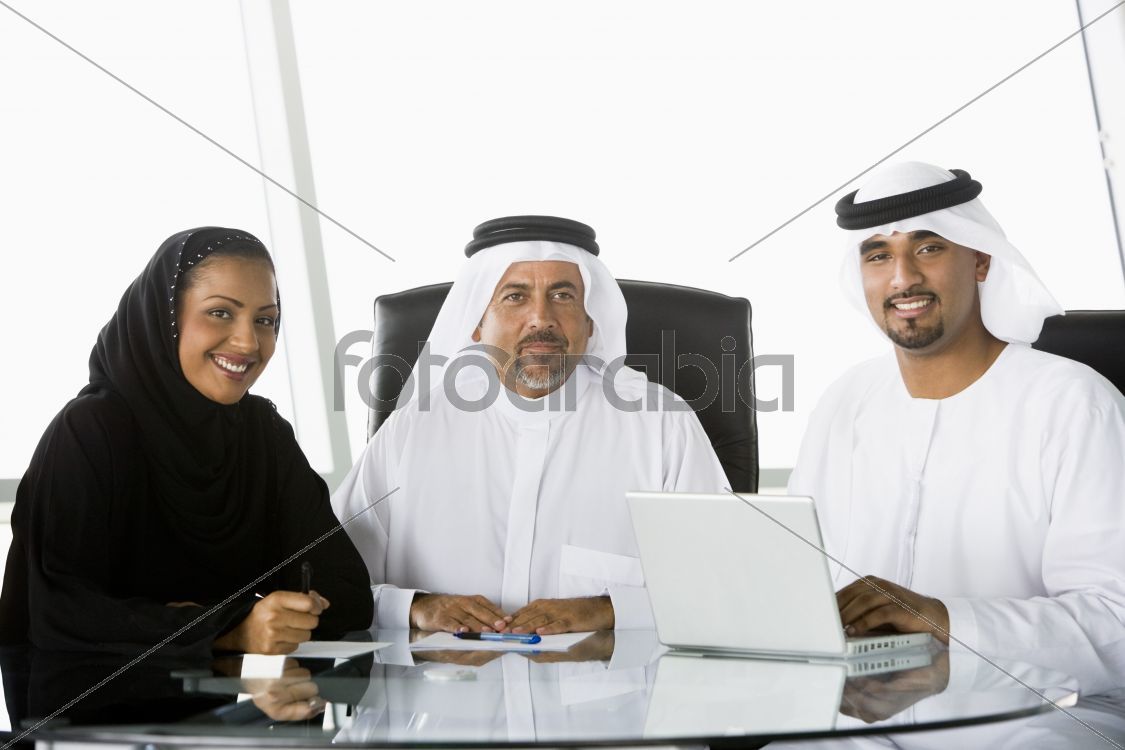 Two Middle Eastern businessmen and a woman beside a laptop