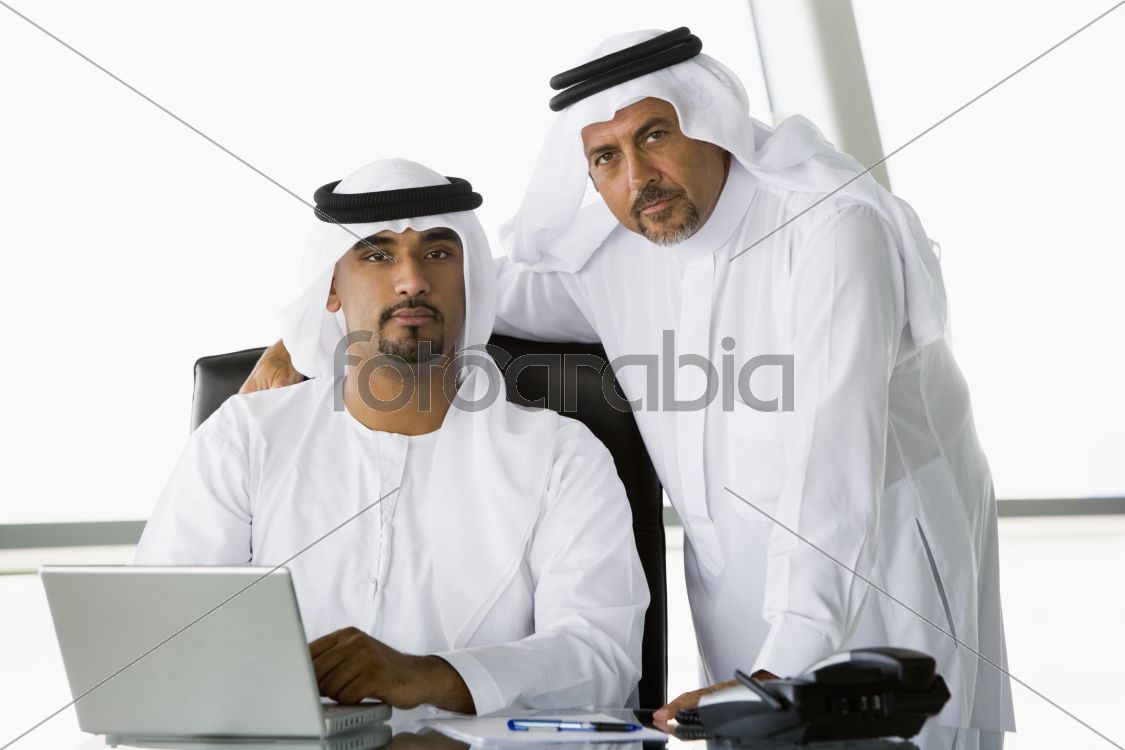 Two Middle Eastern businessmen beside a laptop