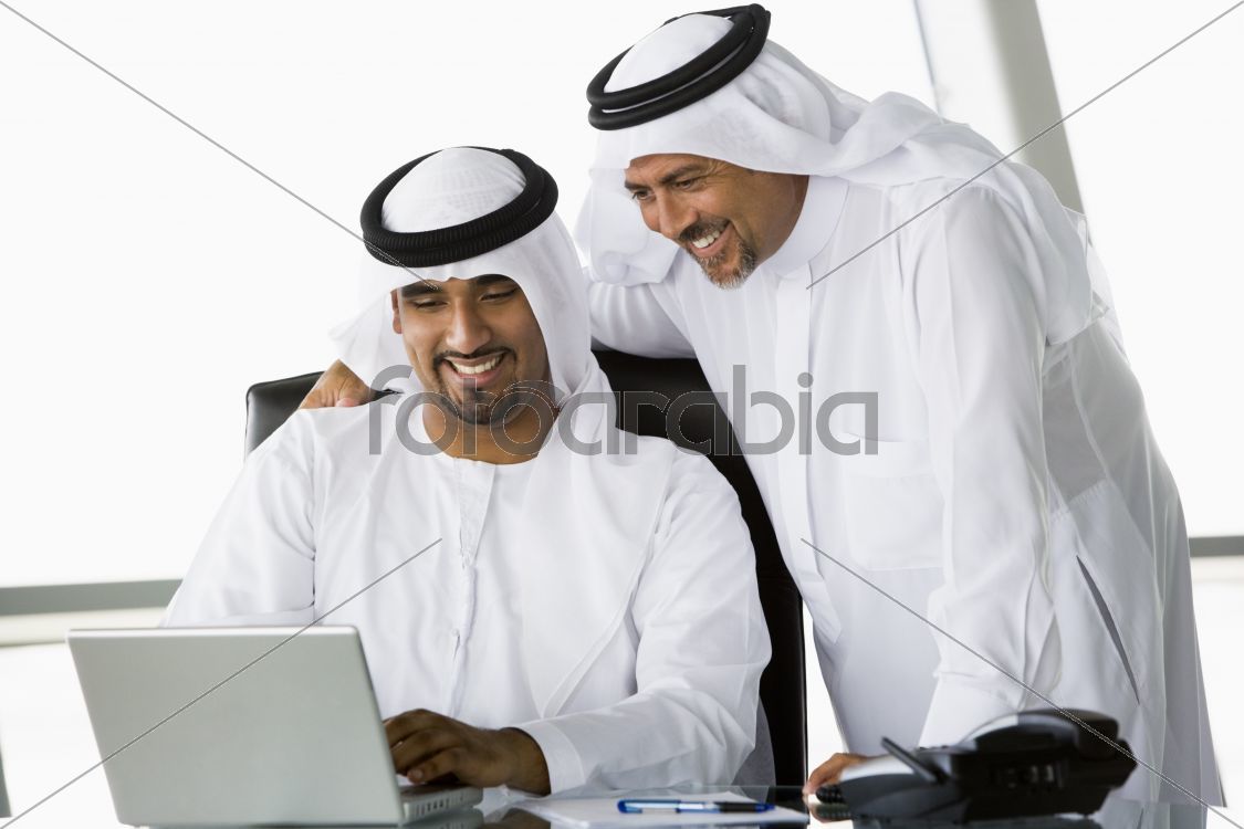 Two Middle Eastern businessmen beside a laptop