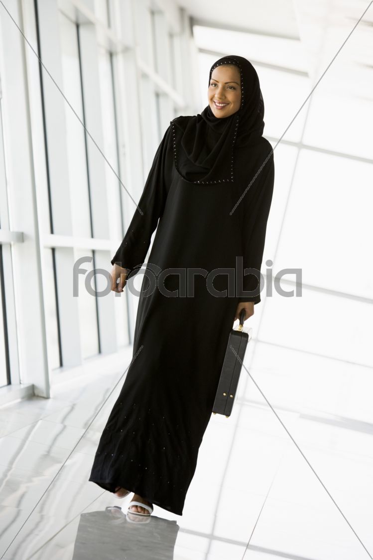 A Middle Eastern businesswoman walking in a corridor