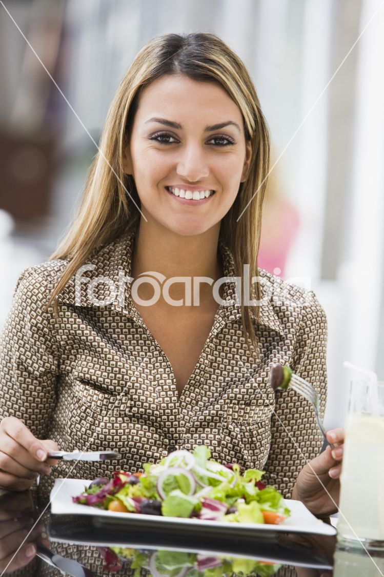 Woman eating salad at cafe