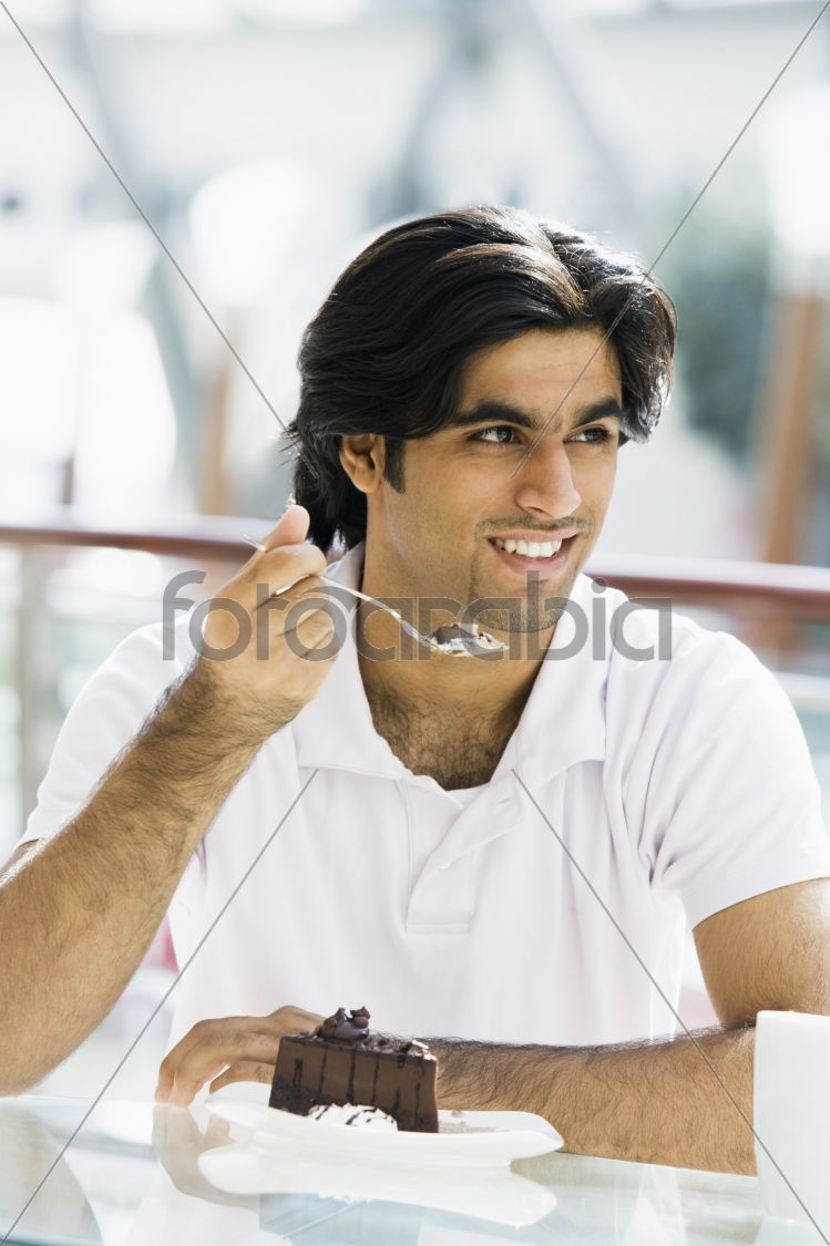 Young man eating cake in cafe