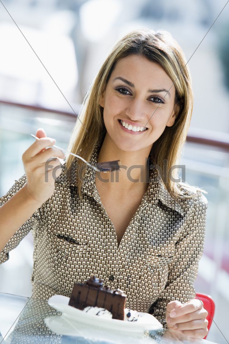 Woman eating chocolate cake in cafe