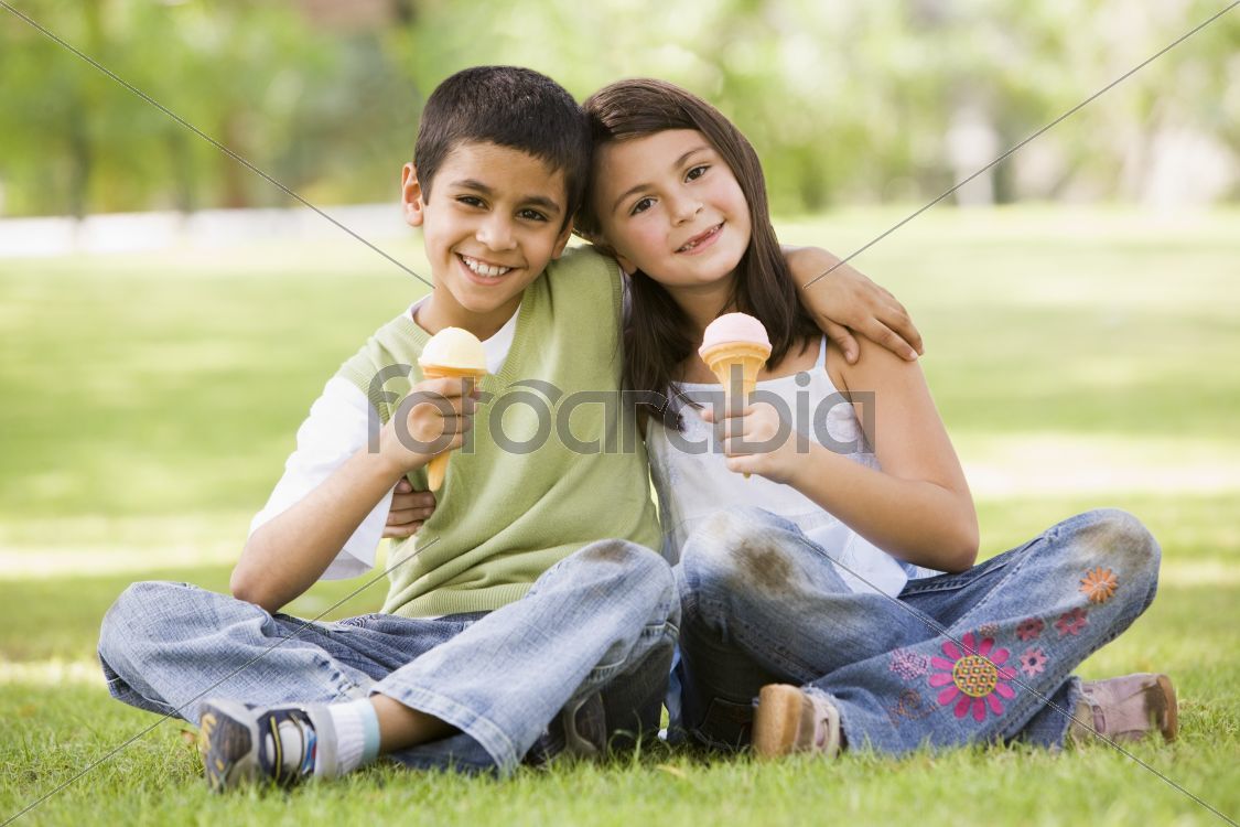Two children eating ice cream in park