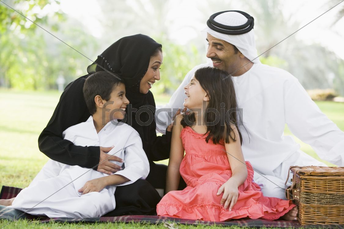 A Middle Eastern family sitting in a park