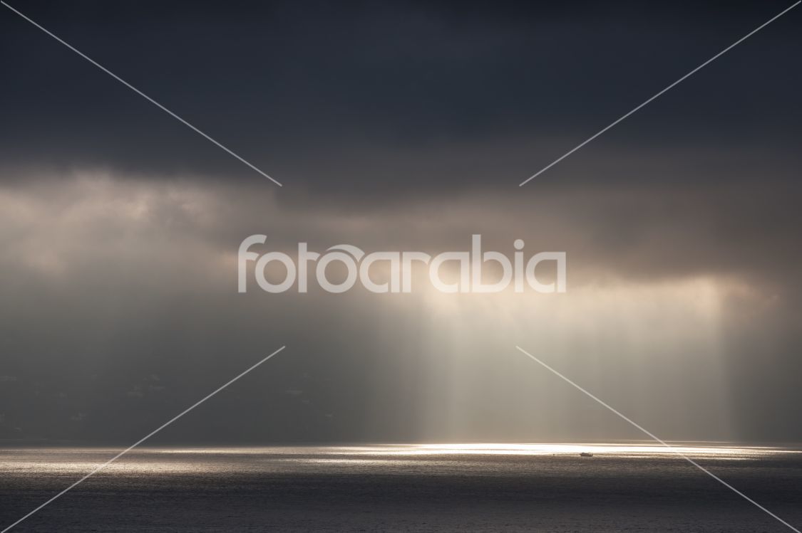 Bright sunlight goes through dark stormy clouds. Tangier bay, Morocco